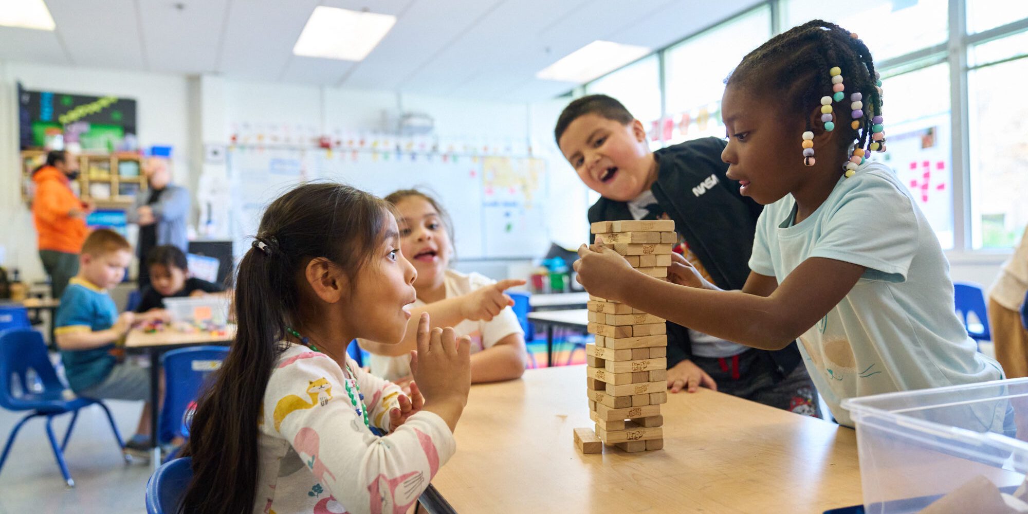 An image of Latino and Black elementary students playing a game together.